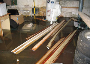 A severely flooding basement in Peterborough, with lumber and personal items floating in a foot of water
