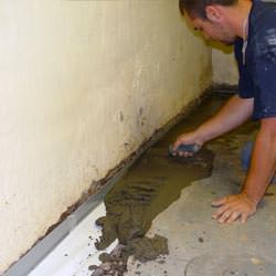 A basement waterproofer installing a perimeter drain system in Port Hope