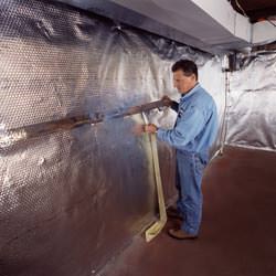 Installation of a radiant heat and vapor barrier on a basement wall in Maple